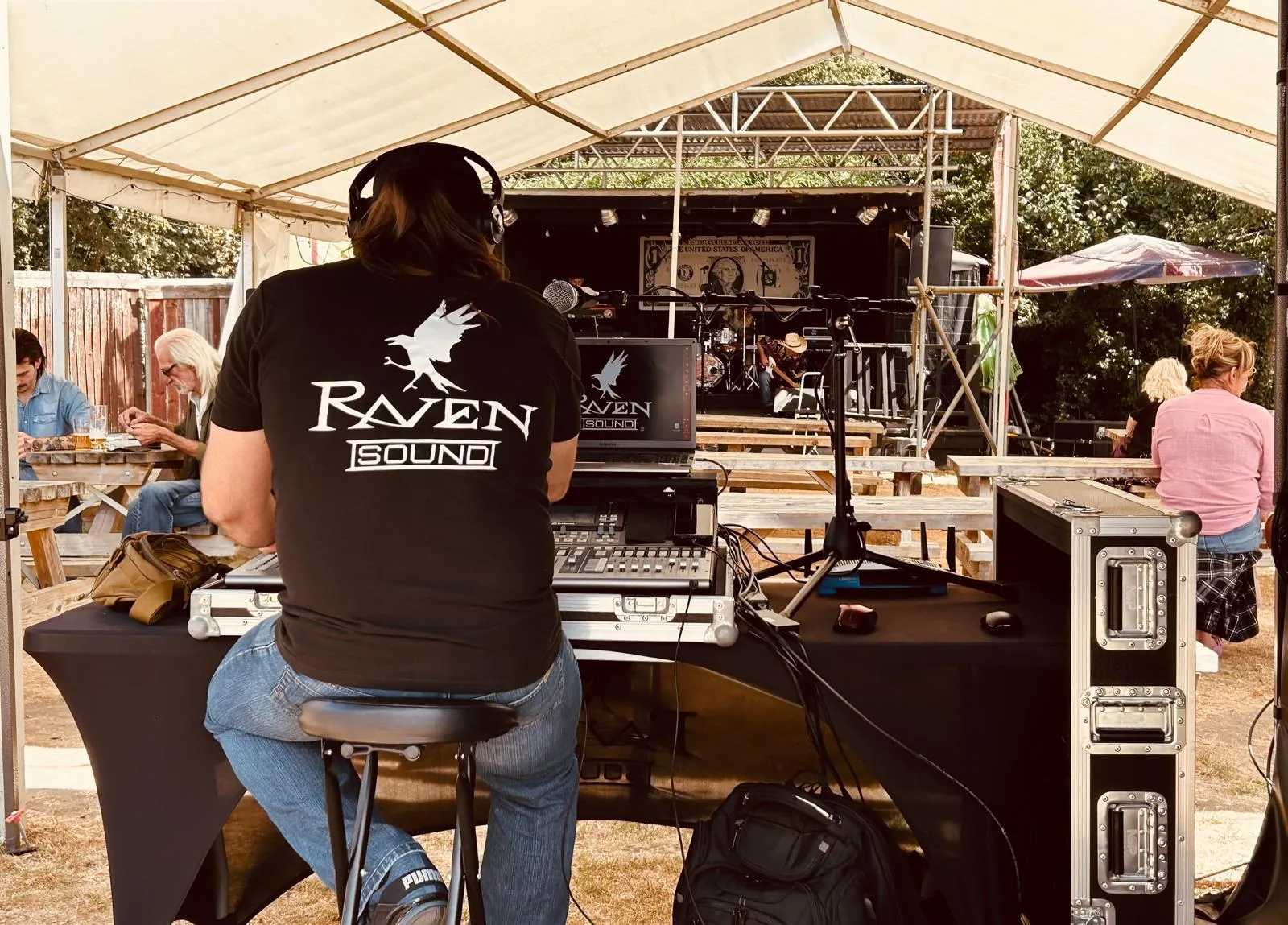 Jamie at the Raven Sound desk under a marquee, with a band on stage behind